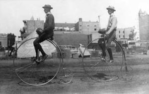 Vintage Penny Farthing Tricycles for Adults Two men riding high wheel penny farthing tricycles. Classic vintage design.