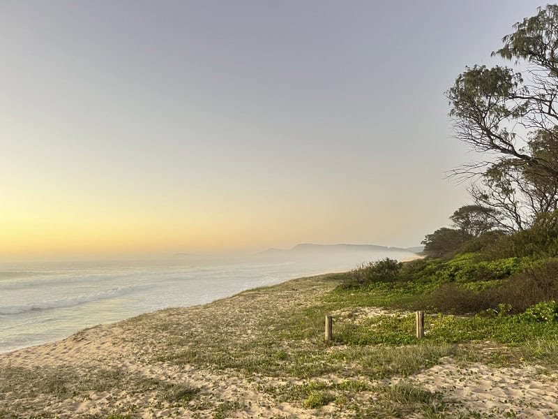 A serene beach at sunset in Australia. A tranquil scene with calm sea and clear sky.