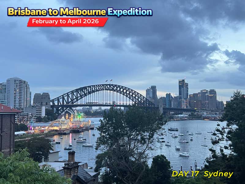 Sydney Harbour Bridge and city skyline on a cloudy day. Boats are scattered across the water.