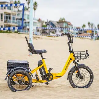 A yellow electric tricycle with a black seat and basket on a sandy beach in Australia. Perfect for seniors and mobility needs.