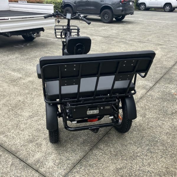 Rear view of black electric tricycle in car park Black electric adult tricycle with large rear seat. Disability mobility tricycle with sturdy frame.