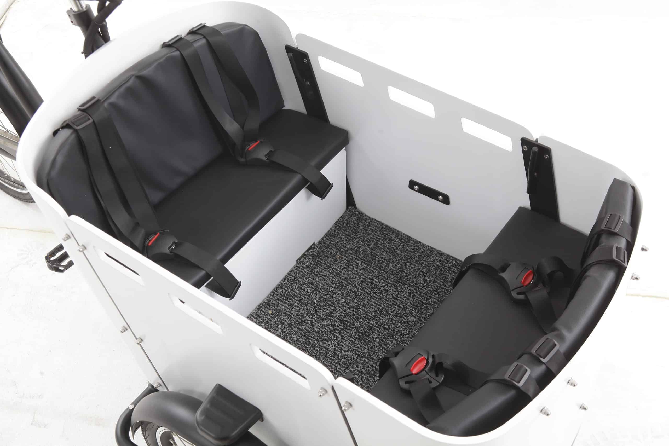 Cargo tricycle with two black seats and grey floor. Perfect for mobility and transport.