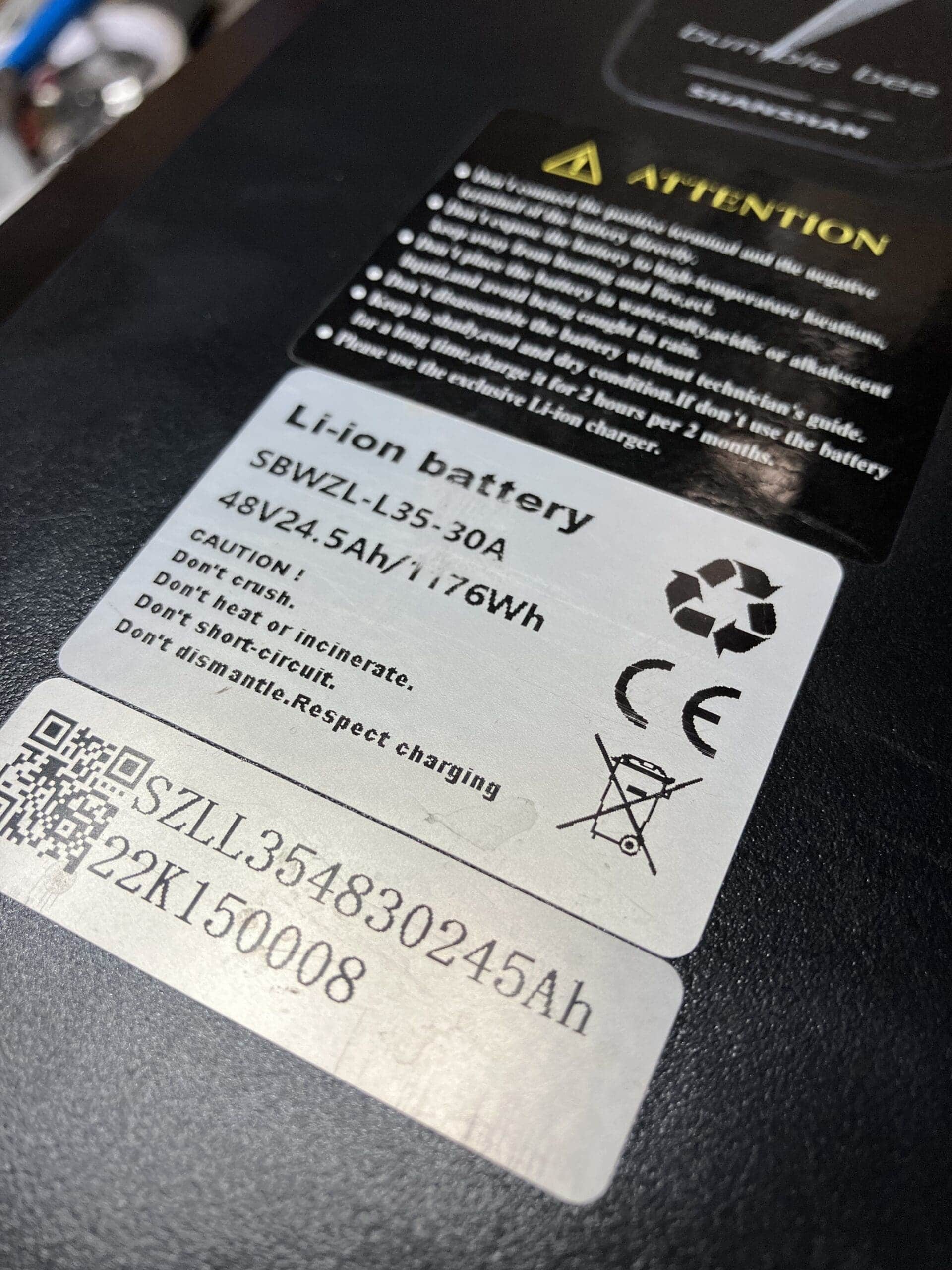 A close-up of a lithium-ion battery label on an electric tricycle. The label includes specifications and safety information.